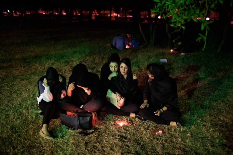 Some girls watching the boys performing during the Ashura. Also young Iranians, which belief, lifestyle and costumes are banned by the Clergy, partecipate to the Ashura. Iran, Ahvaz, November 2014.