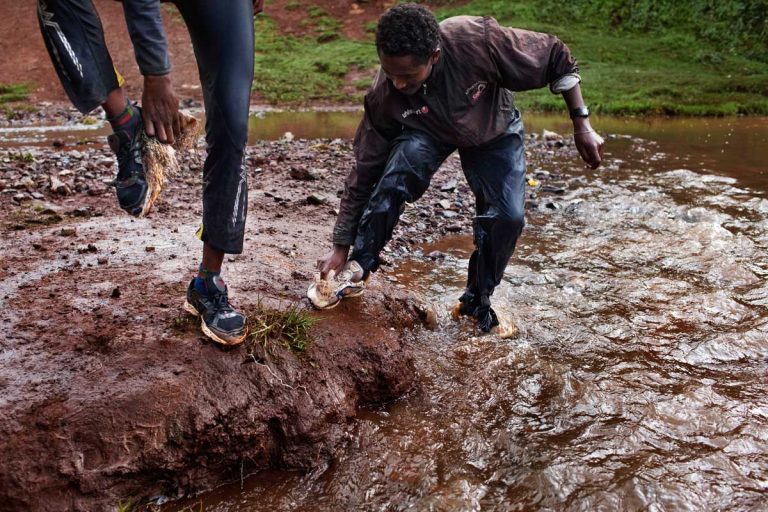 Bekoji, Ethiopia. August 2013. After training, on the way back home, some runners wash their running shoes in the stream between the forest and the town. Most of the runners have just one pair of shoes, running shoes, and they also wear them when not training.