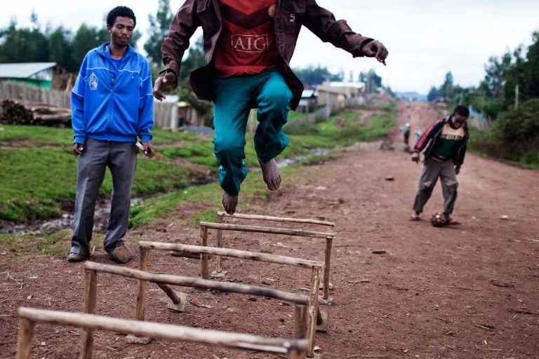 Bekoji, Ethiopia. August 2013. Boys jumping in the street with a homemade obstacle.